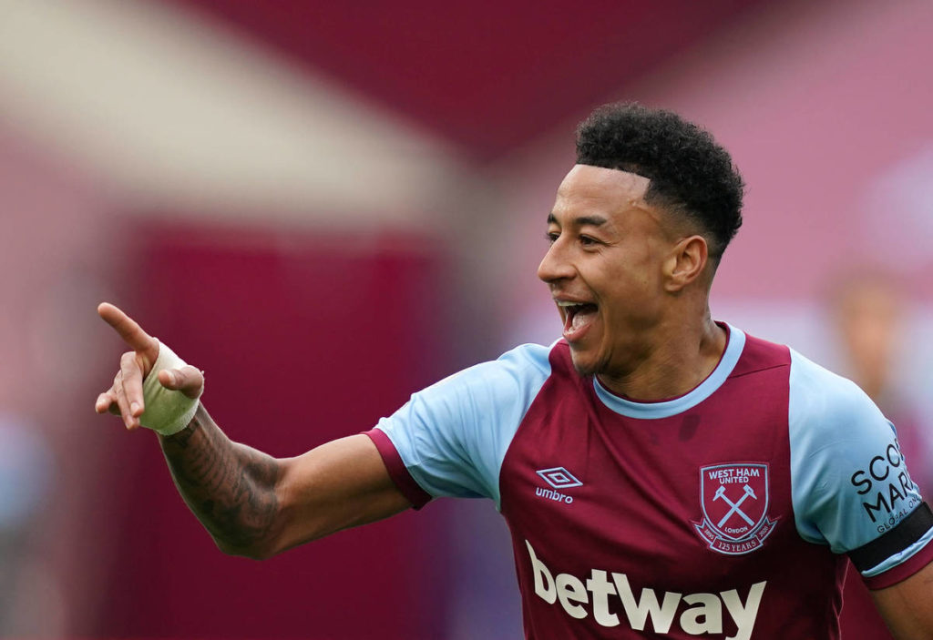 Jesse Lingard in a West Ham shirt in claret and blue with his tongue out and pointing
