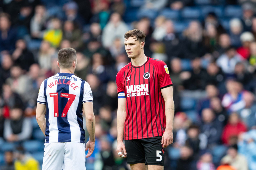 Jake Cooper of Millwall in a red shirt standing in the middle of the shot