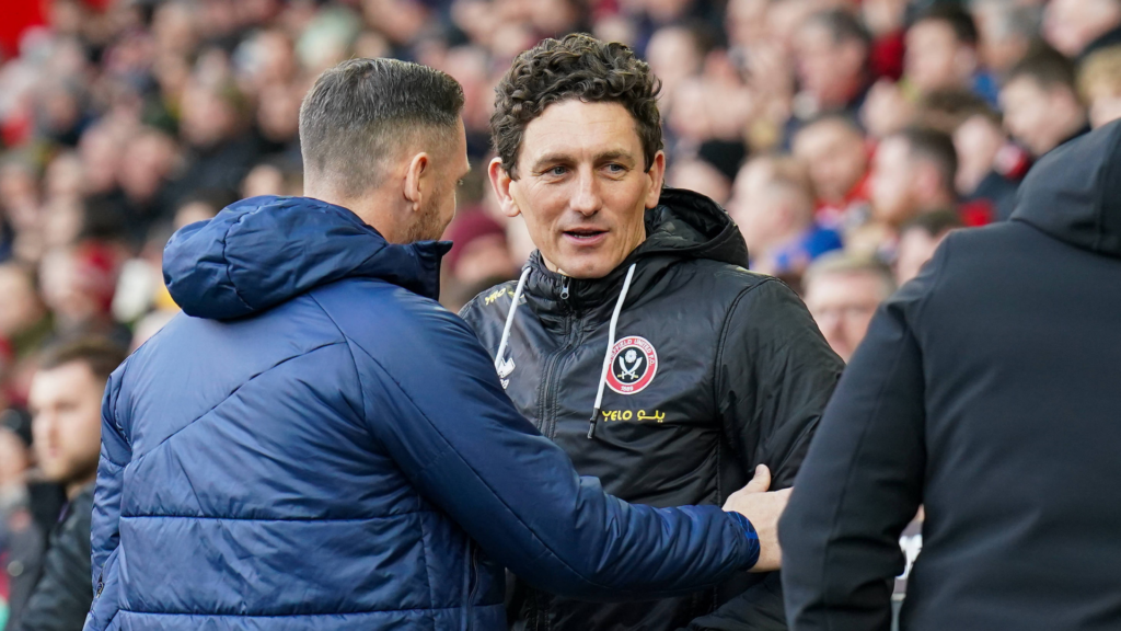 Keith Andrews, Brentford in a Sheffield United black coat hugging a rival coach