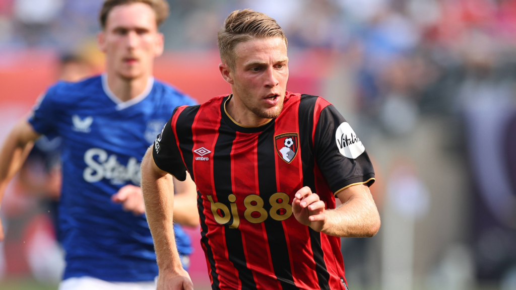 Adrien Truffert in red and black Bournemouth kit running with an Everton player in blue behind him in the background