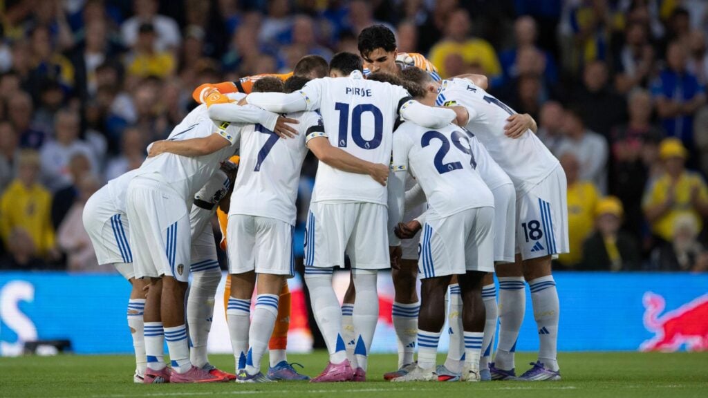 Leeds United's first team huddle around each other.