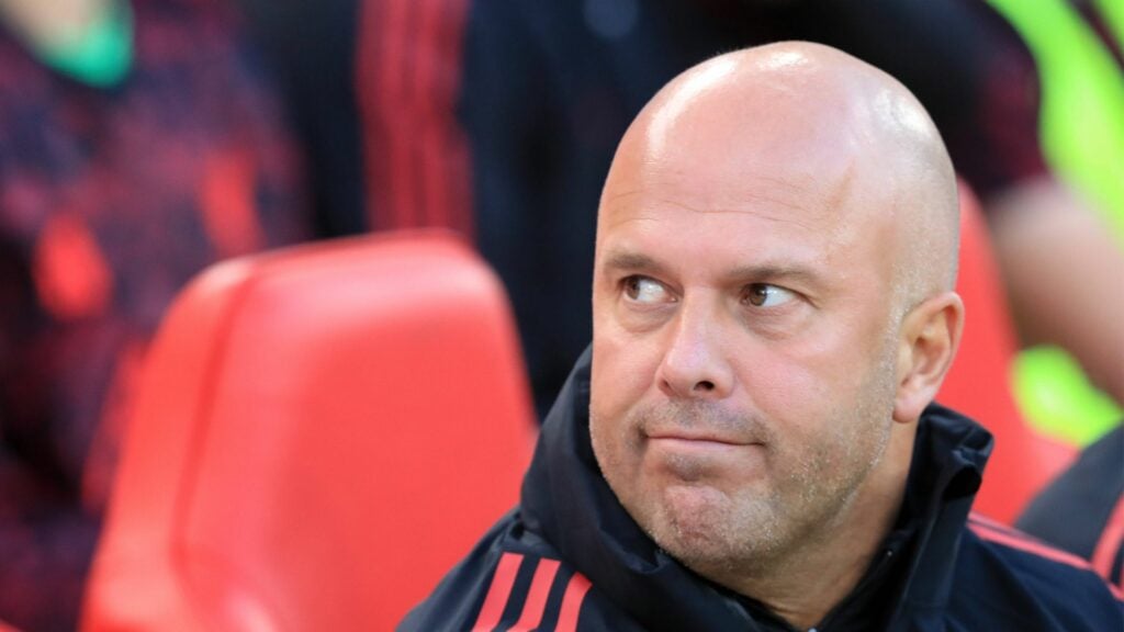Liverpool manager Arne Slot glances to his left while sitting in the dugout.