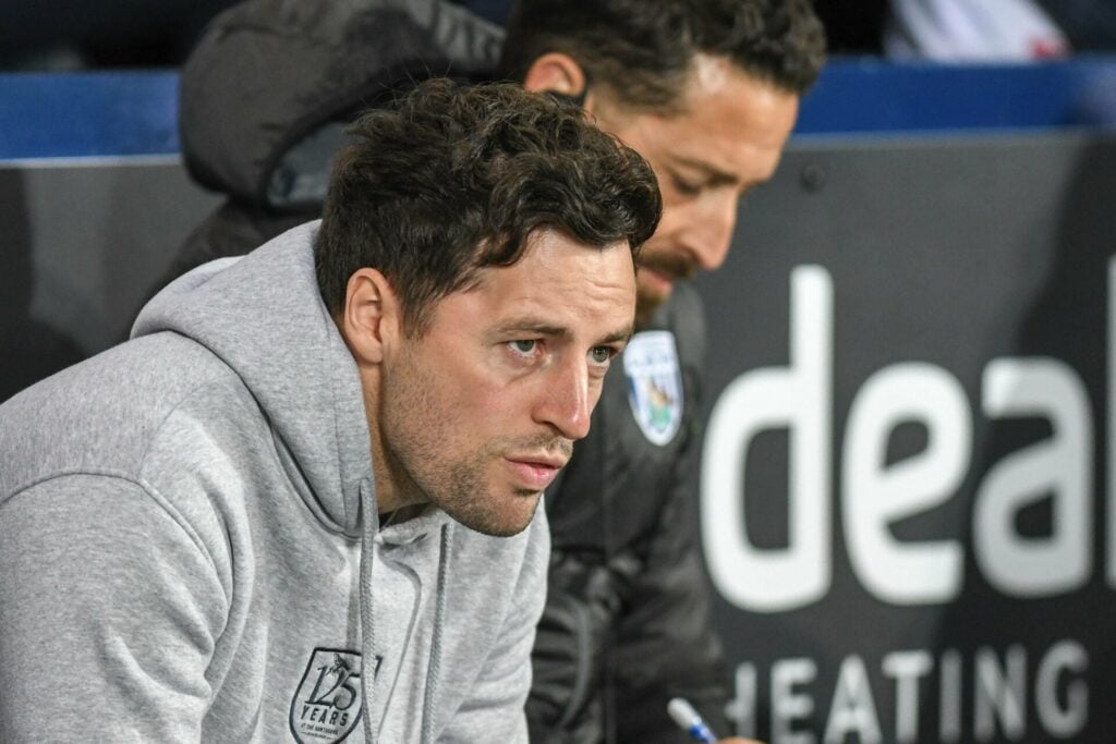 West Brom managed Ryan Mason looks concerned while sitting in the dugout.