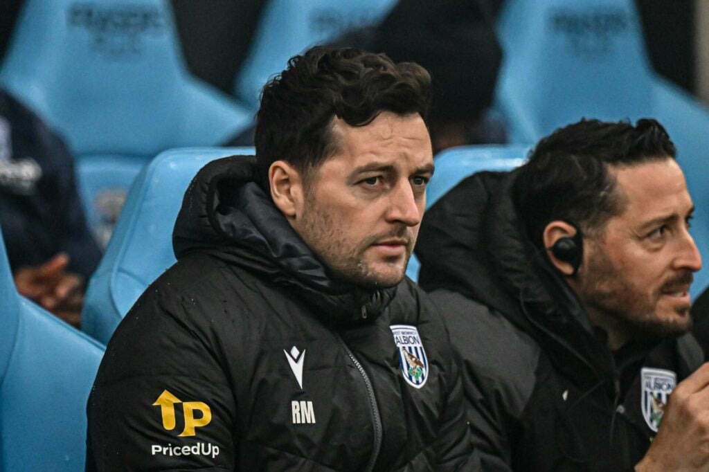 West Brom manager Ryan Mason looks concerned while sitting in the dugout.