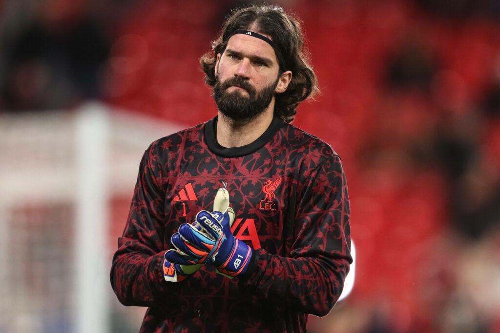 Liverpool goalkeeper Alisson presses his hands together while warming up for a Champions League game.